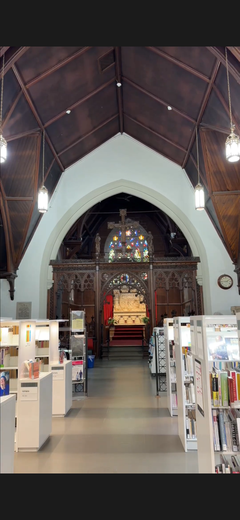Intérieur de la bibliothèque Claire-Martin à Québec, aménagée dans une ancienne église avec une voûte en bois, des vitraux colorés et des étagères de livres.